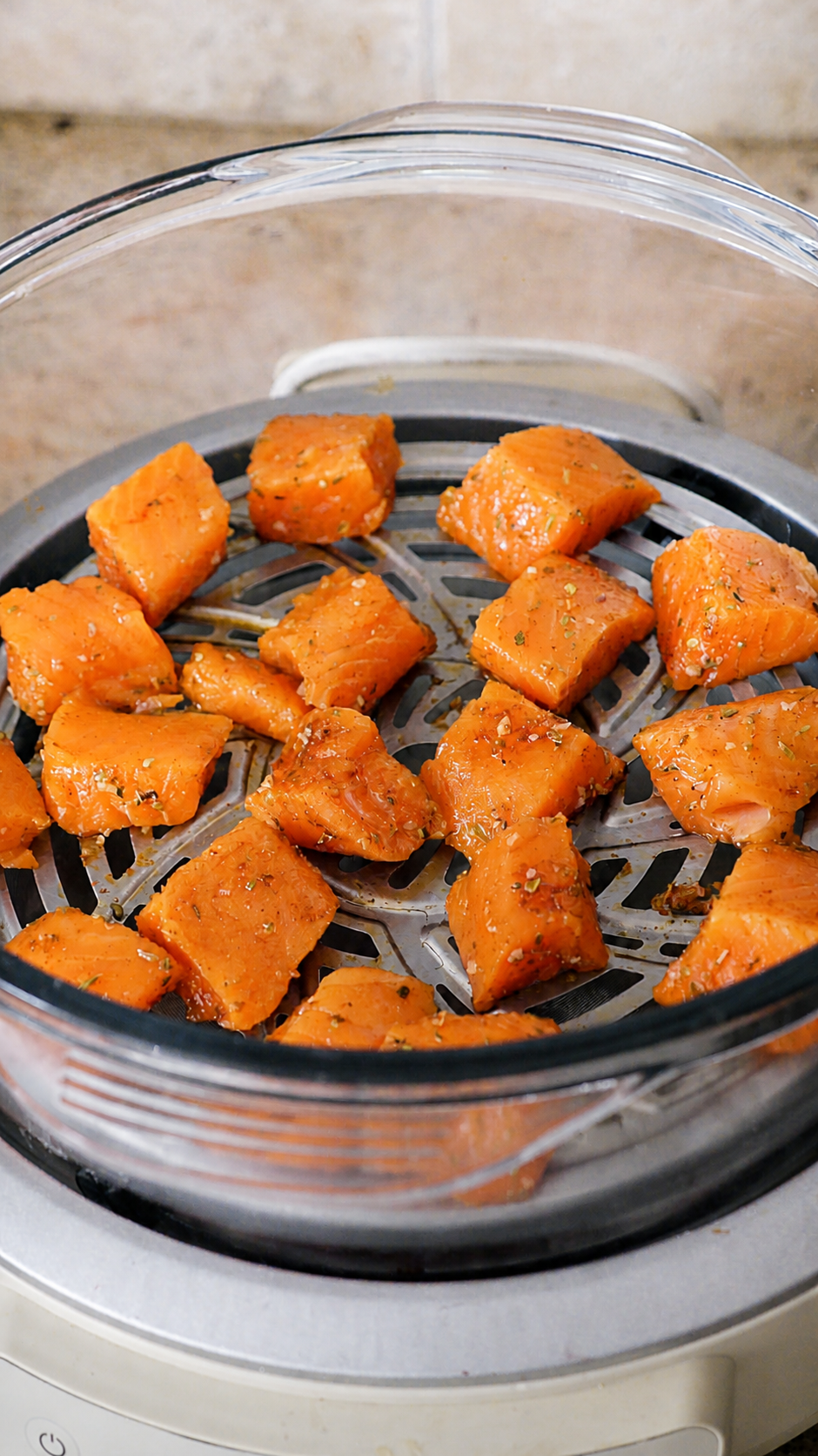 Seasoned steelhead cubes spaced out in an air fryer basket before cooking