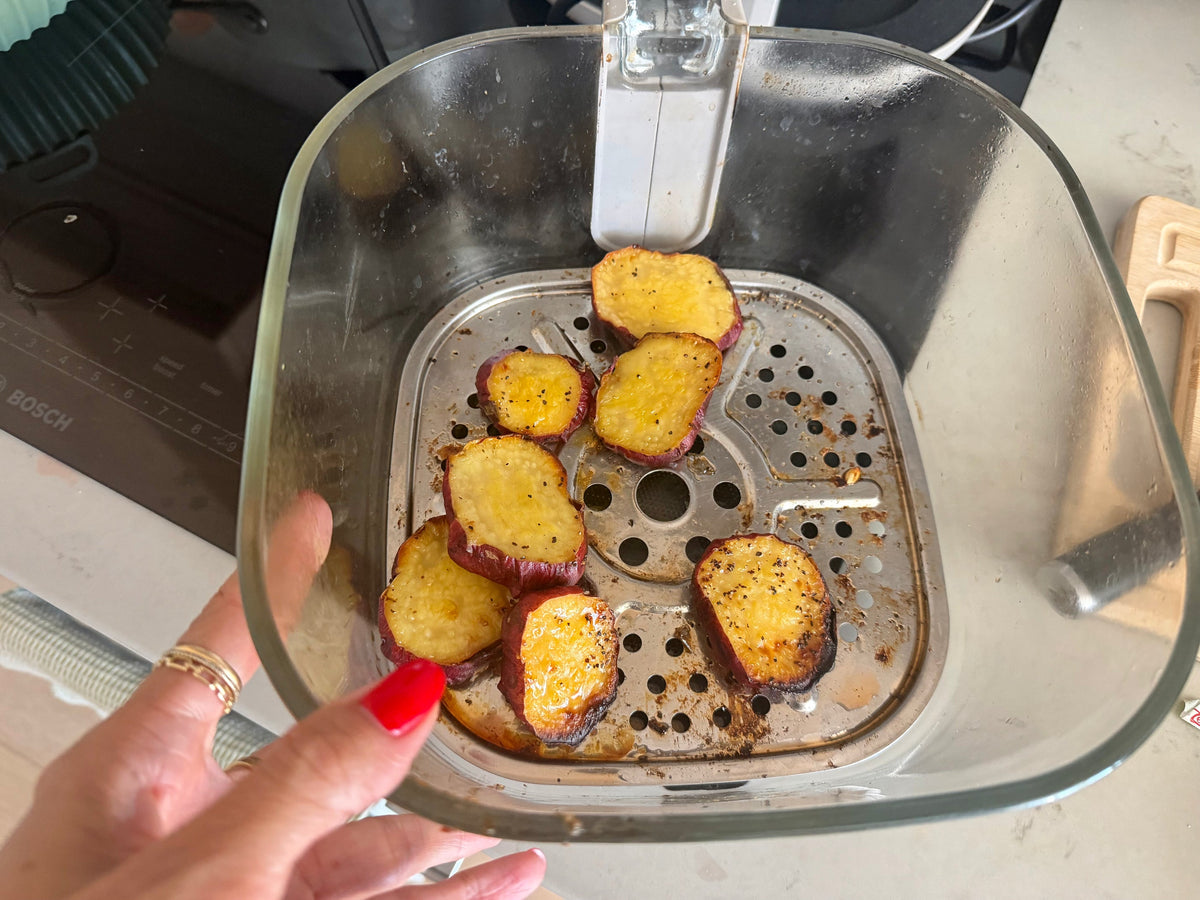 Japanese sweet potato rounds roasted golden in an air fryer basket with olive oil, sea salt, and black pepper