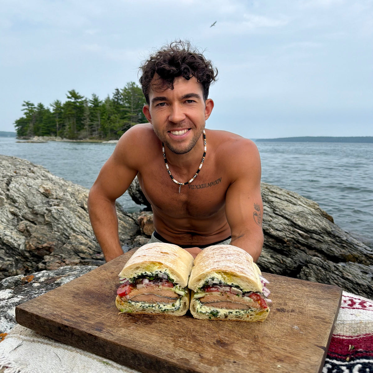 Jason Pabst crouched behind the finished smoked trout sandwich on a rock at the shoreline