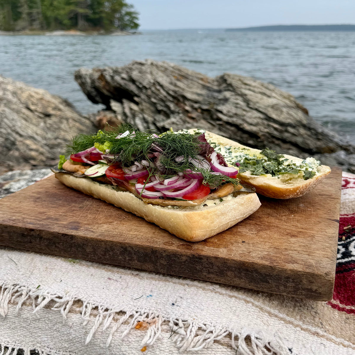 The open sandwich fully loaded with smoked trout, tomato, cucumber, red onion, greens and dill before closing