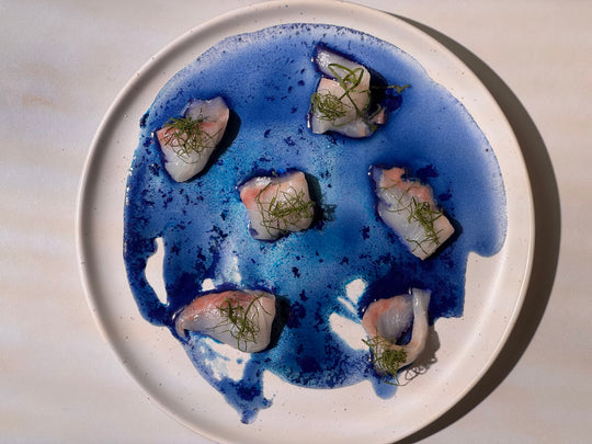 Plate of Blue Spirulina Sea Bream Sashimi, artfully presented with vibrant blue spirulina sauce and fresh sashimi slices, showcasing a sustainable and elegant seafood dish.