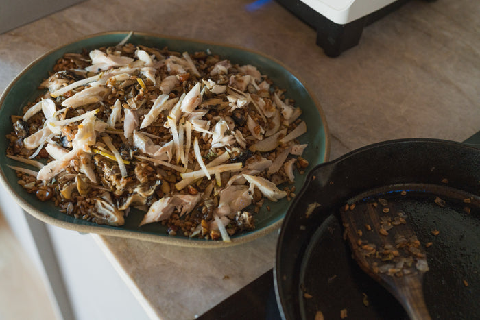 The warm farro and maitake salad in a bowl beside the skillet