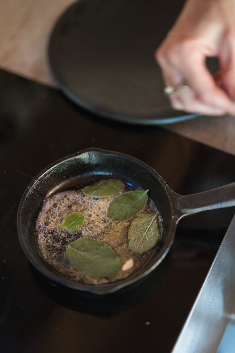 Sage leaves crisping in browning butter in a small cast-iron skillet