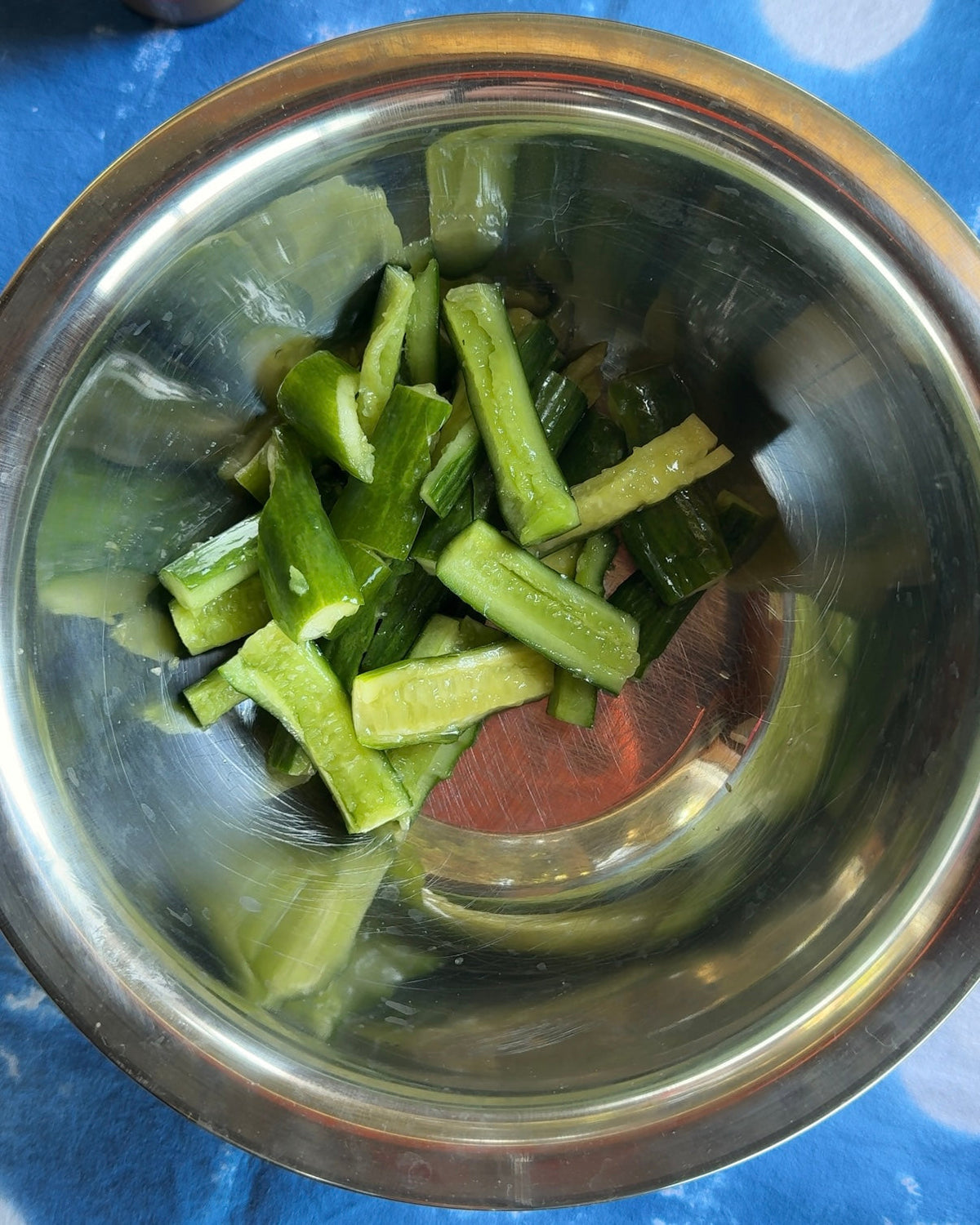 Smashed Persian cucumbers torn into bite-sized pieces in a steel mixing bowl