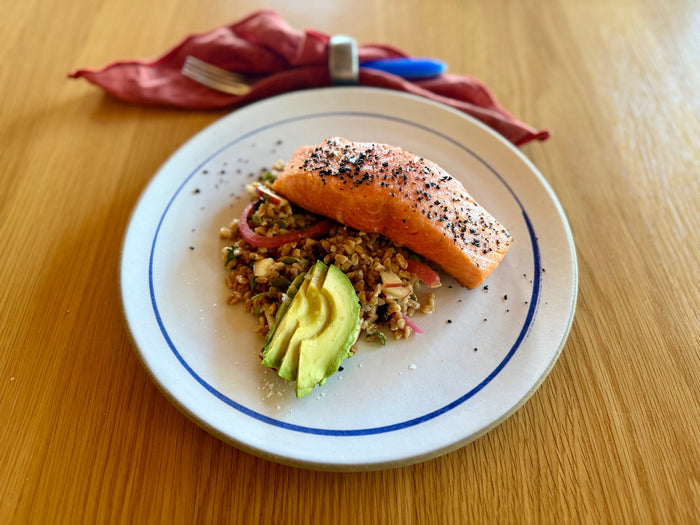 Overhead view of Urfa pepper King Salmon on warm apple and farro salad with avocado and pickled red onion